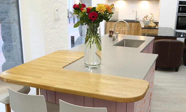 Wooden worktop with pink fitted kitchen cabinets 