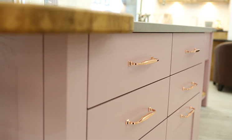 Copper bar handles on a modern pink kitchen cabinet