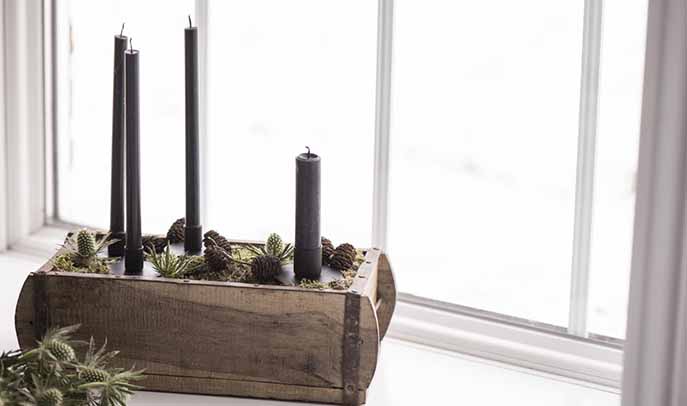 Tall black candles in a wooden box contrast against the scandi white backdrop