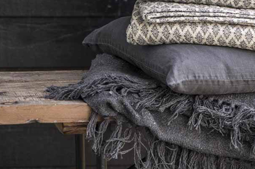Scandi-Nordic textured grey blankets and throws on natural wood bench