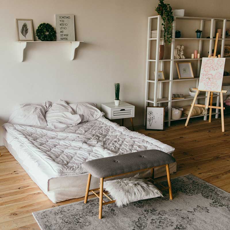 A bedroom with wooden flooring and low bed