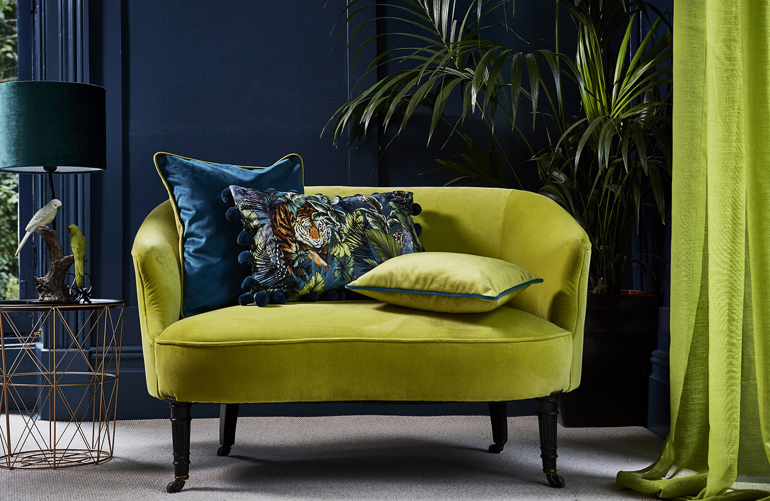 Prestigious Textiles using a moody dark backdrop to enhance the chartreuse coloured velvet sofa