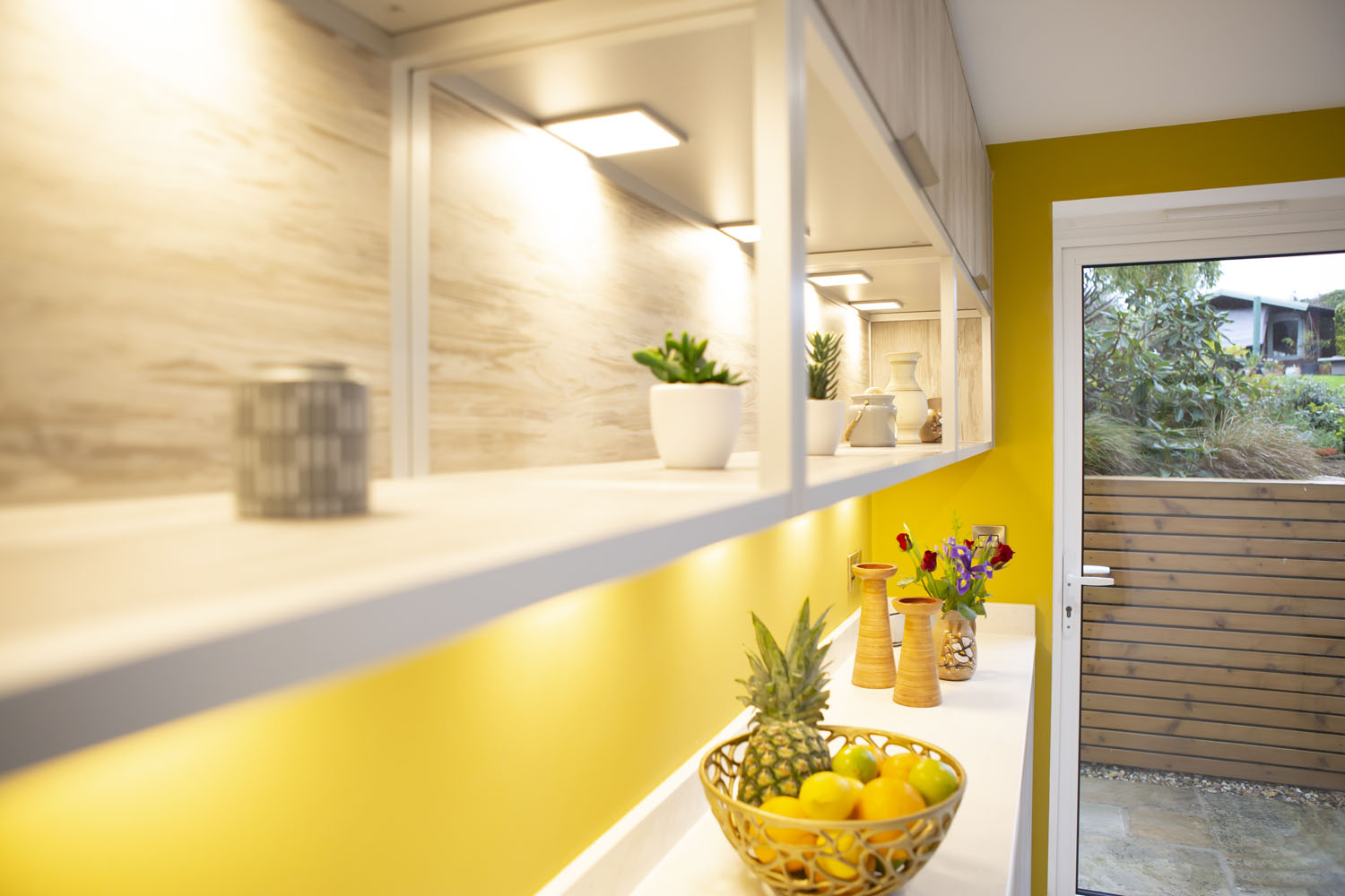 Crown handleless kitchen with open shelving on feature mustard wall