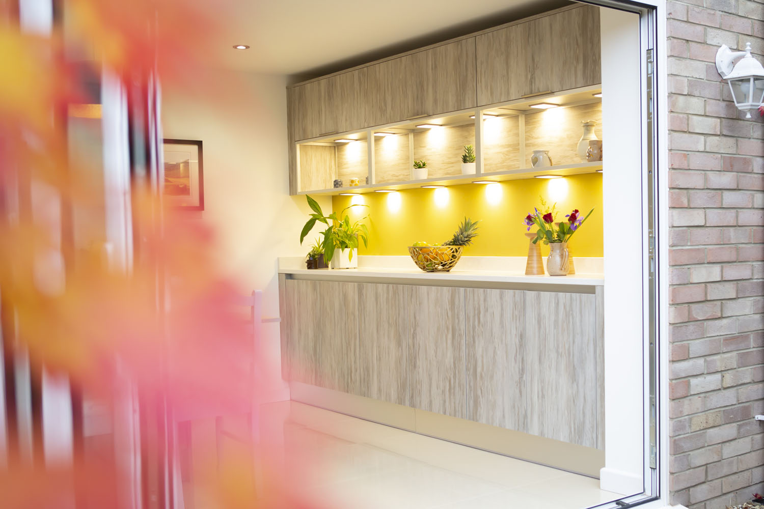 Crown handless kitchen with large kitchen island and open shelving on feature mustard wall