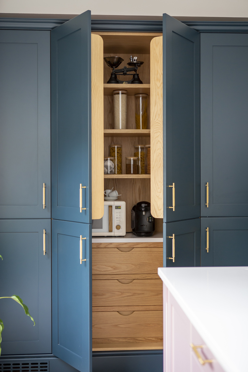 A sneak peak into a beautiful dark blue pantry with oak shelves