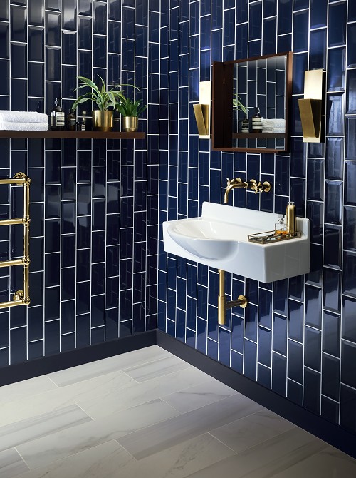 A blue tiled bathroom with sink and mirror