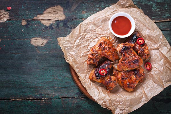 A plate of barbecued chicken with a dipping sauce
