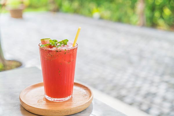 A pink coloured cocktail with a straw